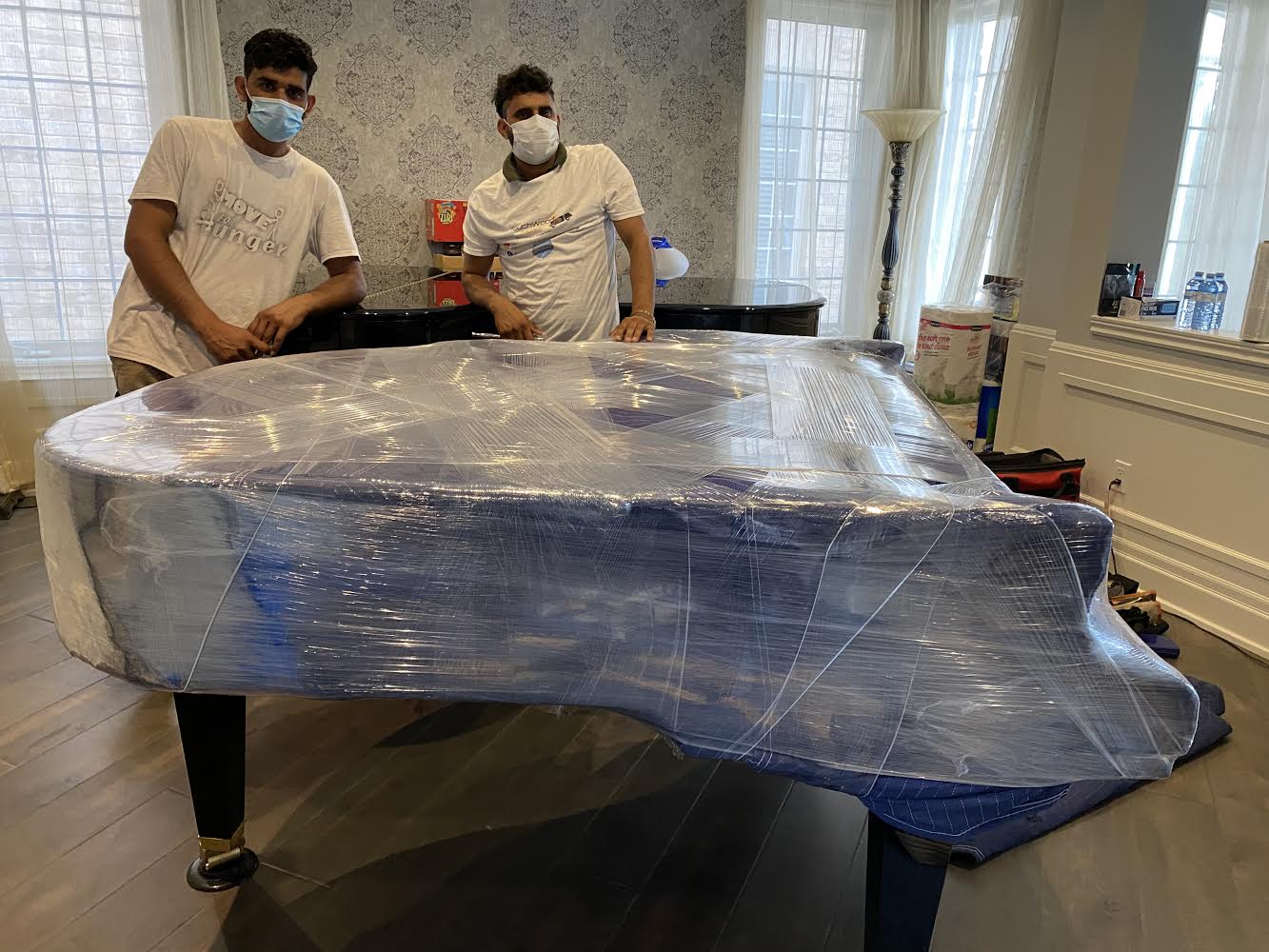 Expert movers packing and moving a parlor grand piano carefully